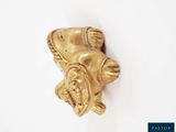 a gold figurine on a white surface with a white background