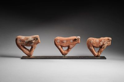 three carved figurines of birds on a stand