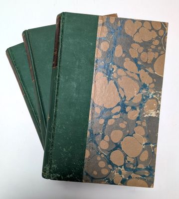 trois livres verts sont empilés les uns sur les autres sur une surface blanche