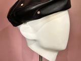 une tête de mannequin blanche coiffée d'un chapeau noir