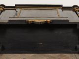 an old black trunk sitting on top of a wooden floor next to a white wall