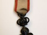 une vieille médaille à laquelle est accroché un ruban rouge sur le côté