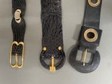 three belts are lined up on a table with gold buckles