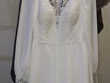 wedding dress hanging on a hanger in front of a stone wall