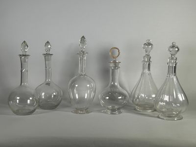 quatre bouteilles en verre transparent sont alignées sur une surface blanche