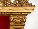 a gold mirror with a red curtain behind it