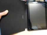 a person holding a tablet and a book on a table