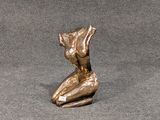 une statue en bronze représentant une femme assise sur une surface grise
