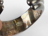a person holding a silver bracelet with a design on it