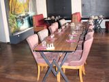 a large dining room with a long table and pink chairs