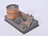 un petit objet métallique représentant un pistolet posé sur un socle