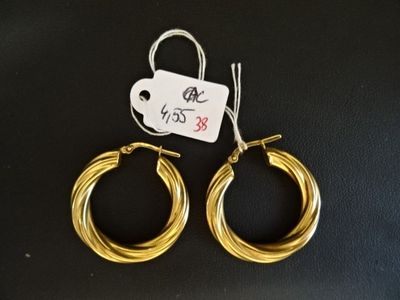 deux boucles d'oreilles en anneau dorées avec une étiquette de prix sur fond noir