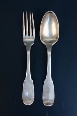 deux cuillères en argent et une fourchette posées sur une table noire