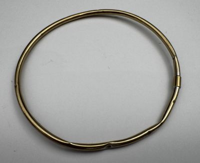a gold bracelet with a metal clasp on a white surface