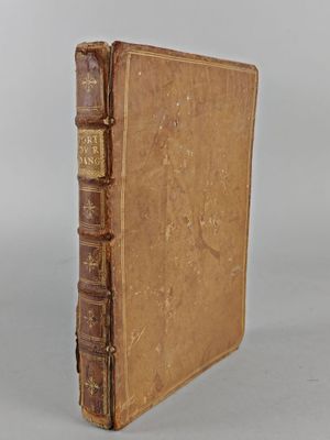 an old book sitting on top of a table next to a white wall