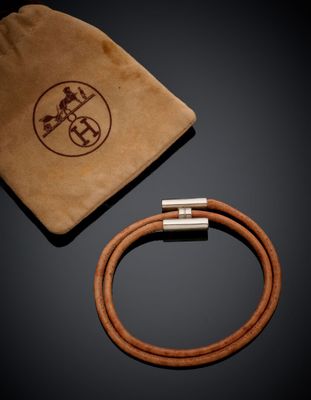 a brown leather bracelet and a brown sued bag on a black surface