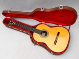 une guitare dans un étui, posée sur une surface blanche