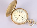 a gold pocket watch sitting on a white surface