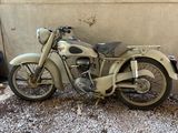 une vieille moto garée sur le gravier