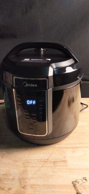 a black and silver electric pressure cooker on a wooden table