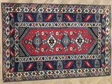 a red, blue and black rug sitting on top of a wooden floor