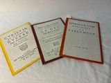three books sitting on top of a bed next to each other