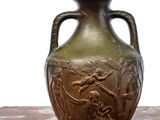 a bronze vase sitting on a table with a white background