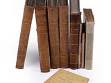 several old books are stacked on top of each other on a white surface