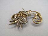 une image d'une broche en or et diamants sur une surface blanche