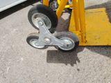 a close up of a yellow hand truck with wheels