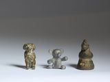 three small bronze figurines of animals and a bear on a white surface