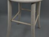 un vieux tabouret blanc avec une assise en bois sur fond gris