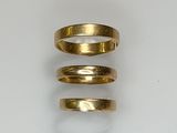 three gold rings sitting on top of each other on a white surface