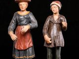two figurines of a man and a woman standing next to each other