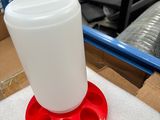 a plastic cup sitting on top of a red and white bird feeder