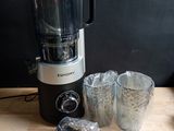 a blender sitting on top of a wooden table next to cups