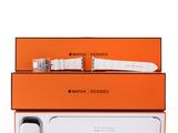 une montre blanche posée sur une boîte orange