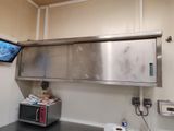un micro-ondes posé sur le plan de travail de la cuisine, avec une télévision accrochée au mur