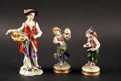 trois figurines représentant un homme et une femme portant des paniers de fruits
