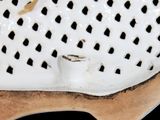 a close up of a white shoe with holes on it