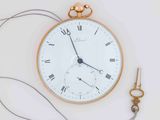 a gold pocket watch and a pair of scissors on a white surface