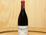 a bottle of wine sitting on top of a barrel