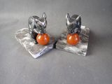 pair of silver cat figurines with orange ball on marble bases