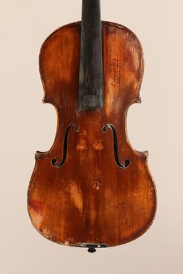 un vieux violon avec un fond en bois et un archet posé sur un support