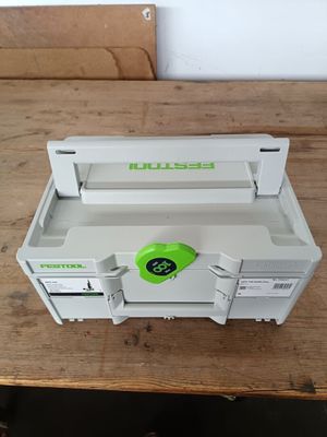 une boîte à outils verte et blanche posée sur une table en bois