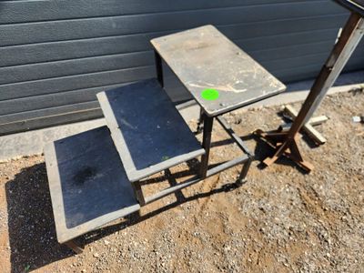 une petite table sur laquelle est posé un tabouret, devant un immeuble