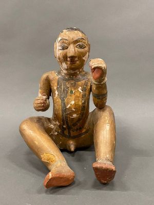 wooden statue of a man sitting on the ground with his hands in the air
