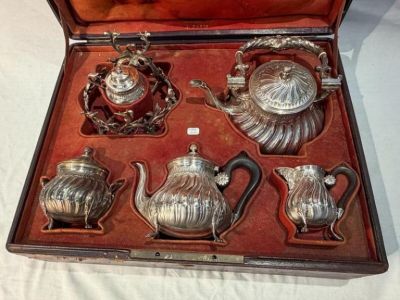 a silver tea set in a case on a table