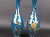 pair of blue vases with gold flowers on them against a gray background