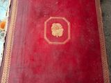 un livre rouge posé sur une table ornée d'un lion doré
